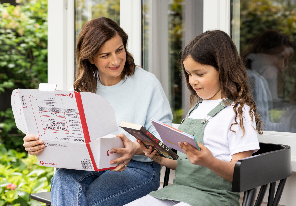 Mother holding Australia Post box with daughter looking through contents